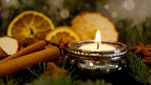 Christmas candle, cinnamon sticks, orange and apple slices amid pine branches
